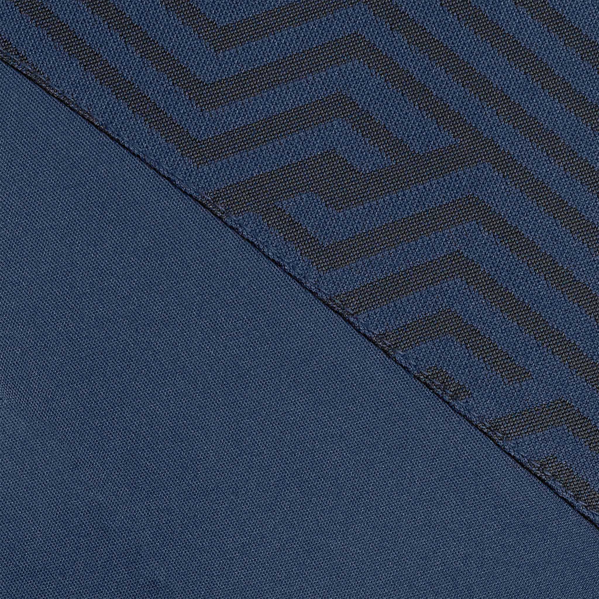 Närbild av Technical Polo Monaco v24 fritidskläder, marinblått tyg med geometriskt labyrintmönster i mörkare toner.