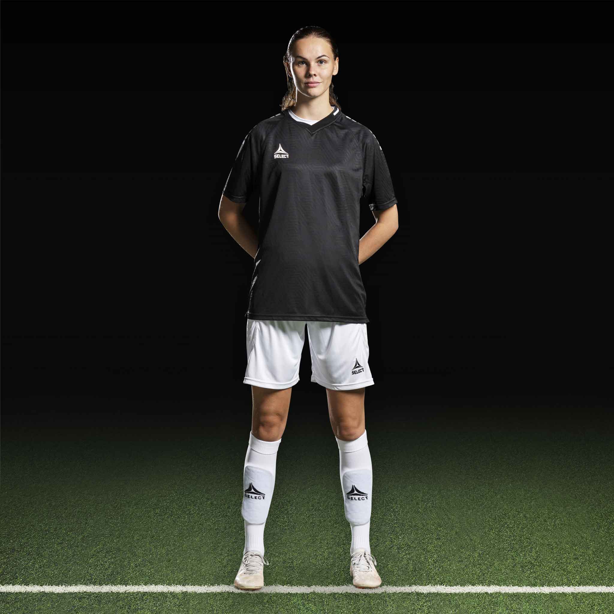 Kvinnlig fotbollsspelare i svart Player shirt S/S Monaco v24, vita shorts och strumpor. Match- och träningskläder.