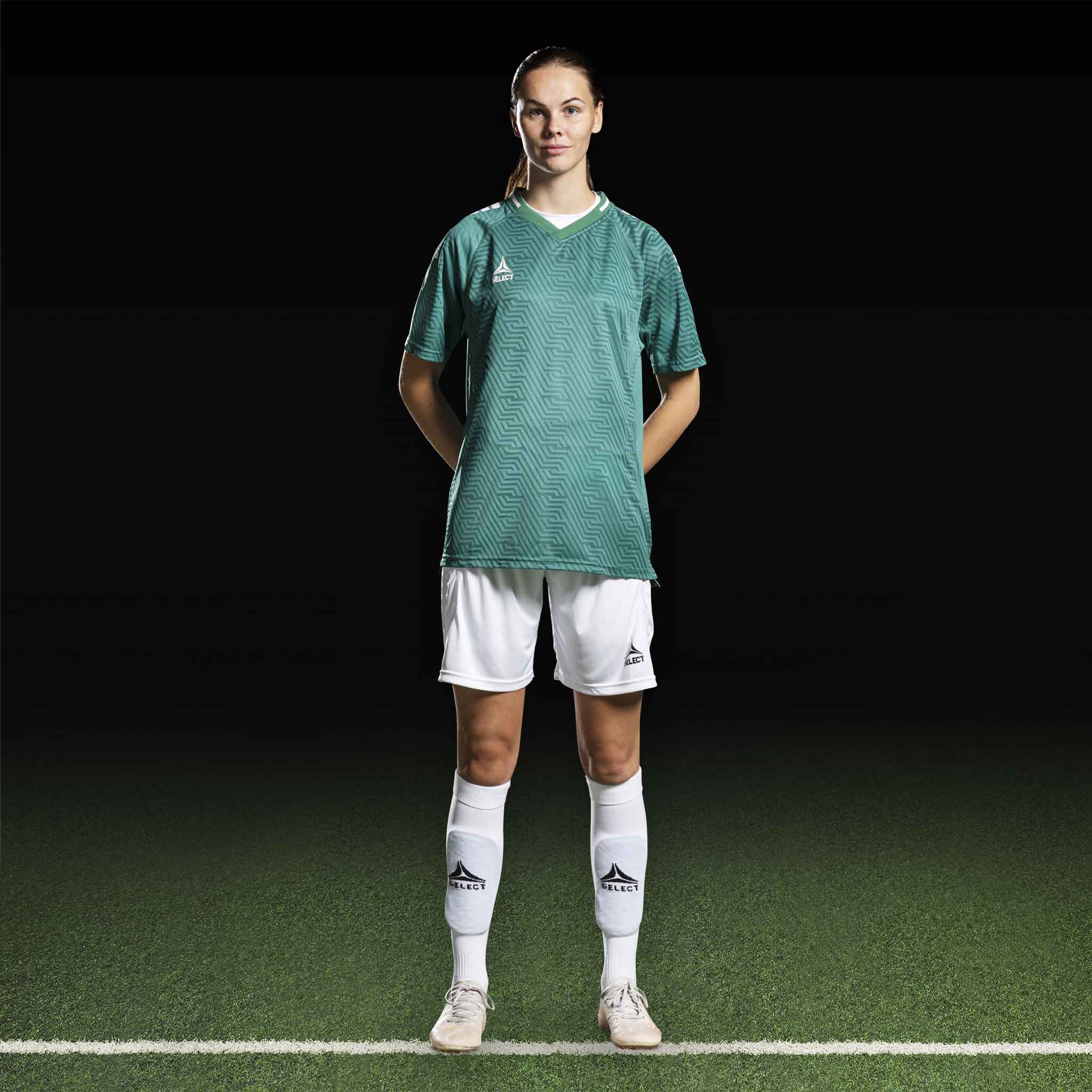 Kvinnlig fotbollsspelare i grön Player shirt S/S Monaco v24 och vita shorts, Match & Training wear, framifrån.