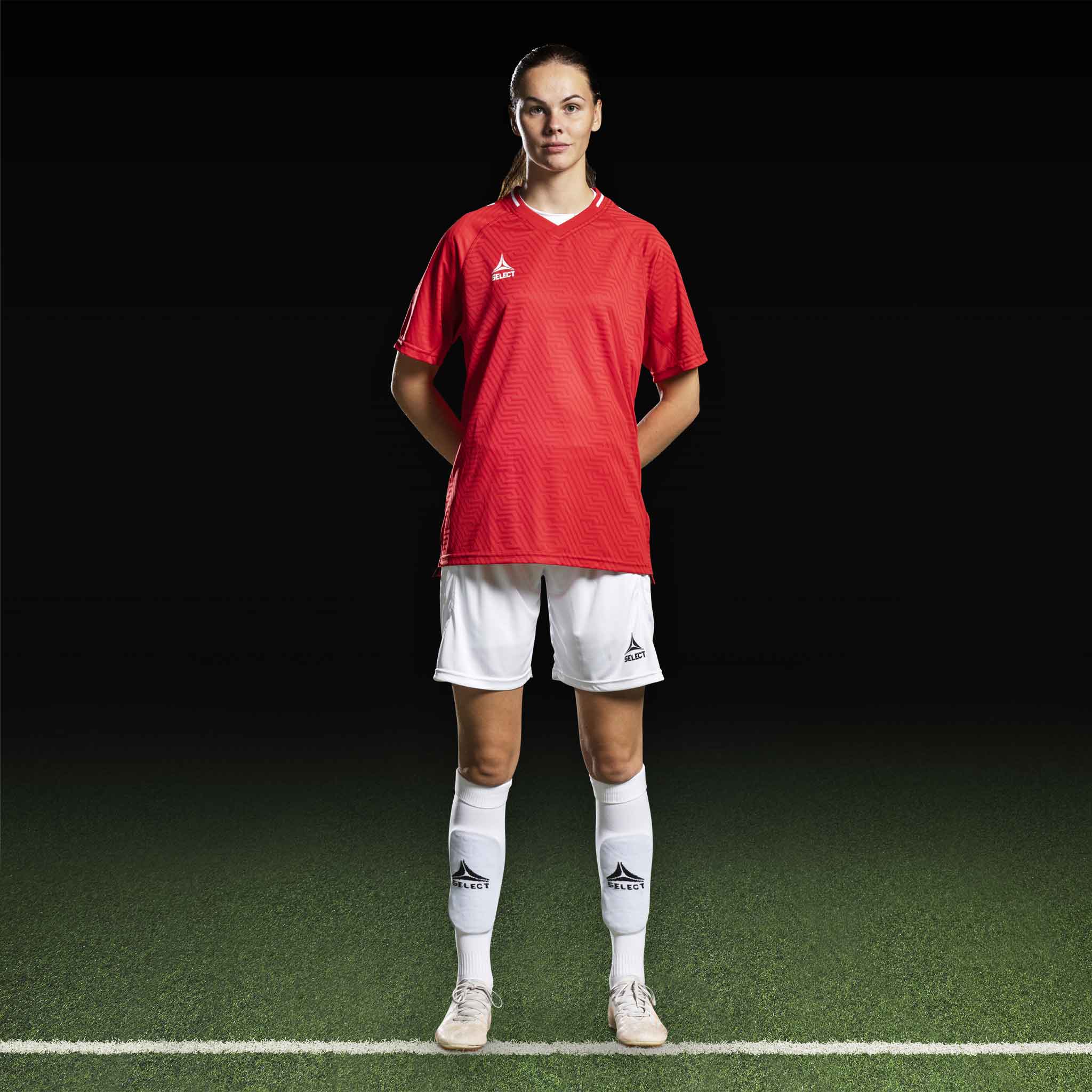 Kvinnlig fotbollsspelare i röd Player shirt S/S Monaco v24, vita shorts och strumpor. Match & Training wear, framifrån.
