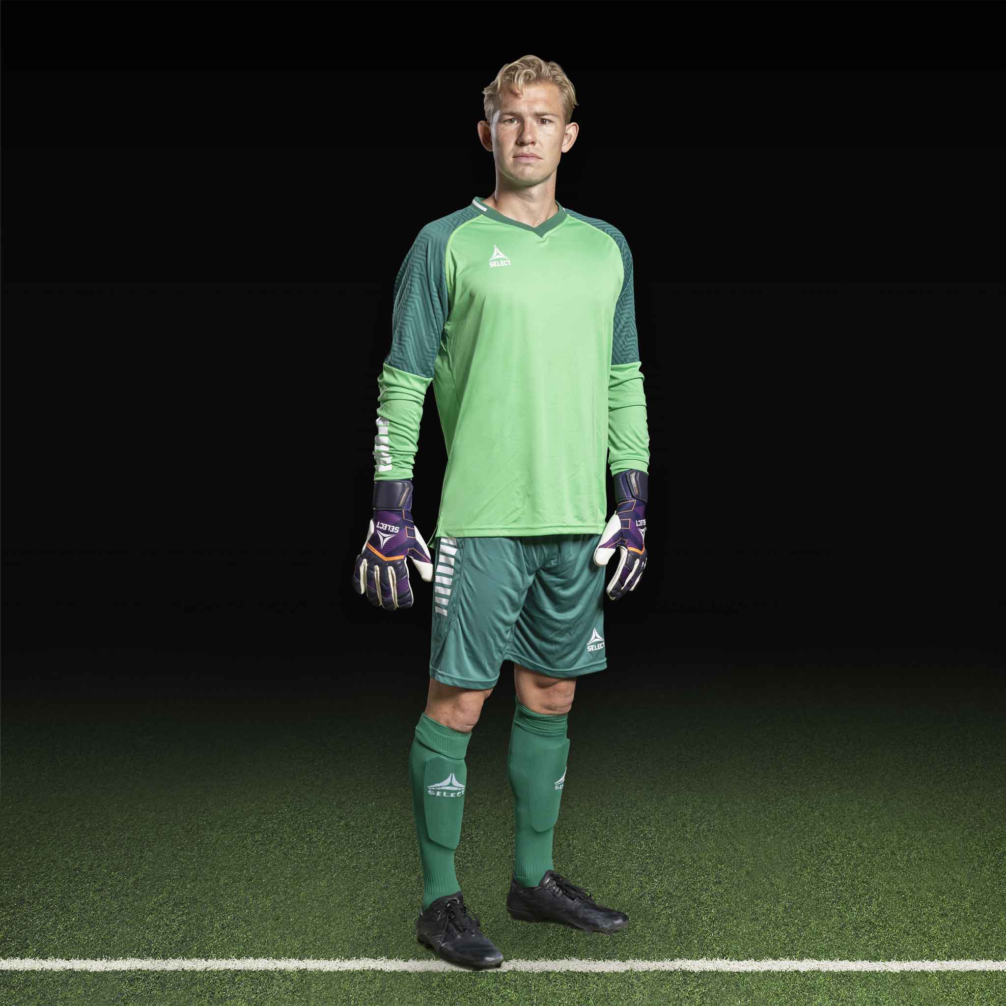 Manlig fotbollsspelare i grön Goalkeeper shirt Monaco v24, målvaktskläder, framifrån med handskar på plan.