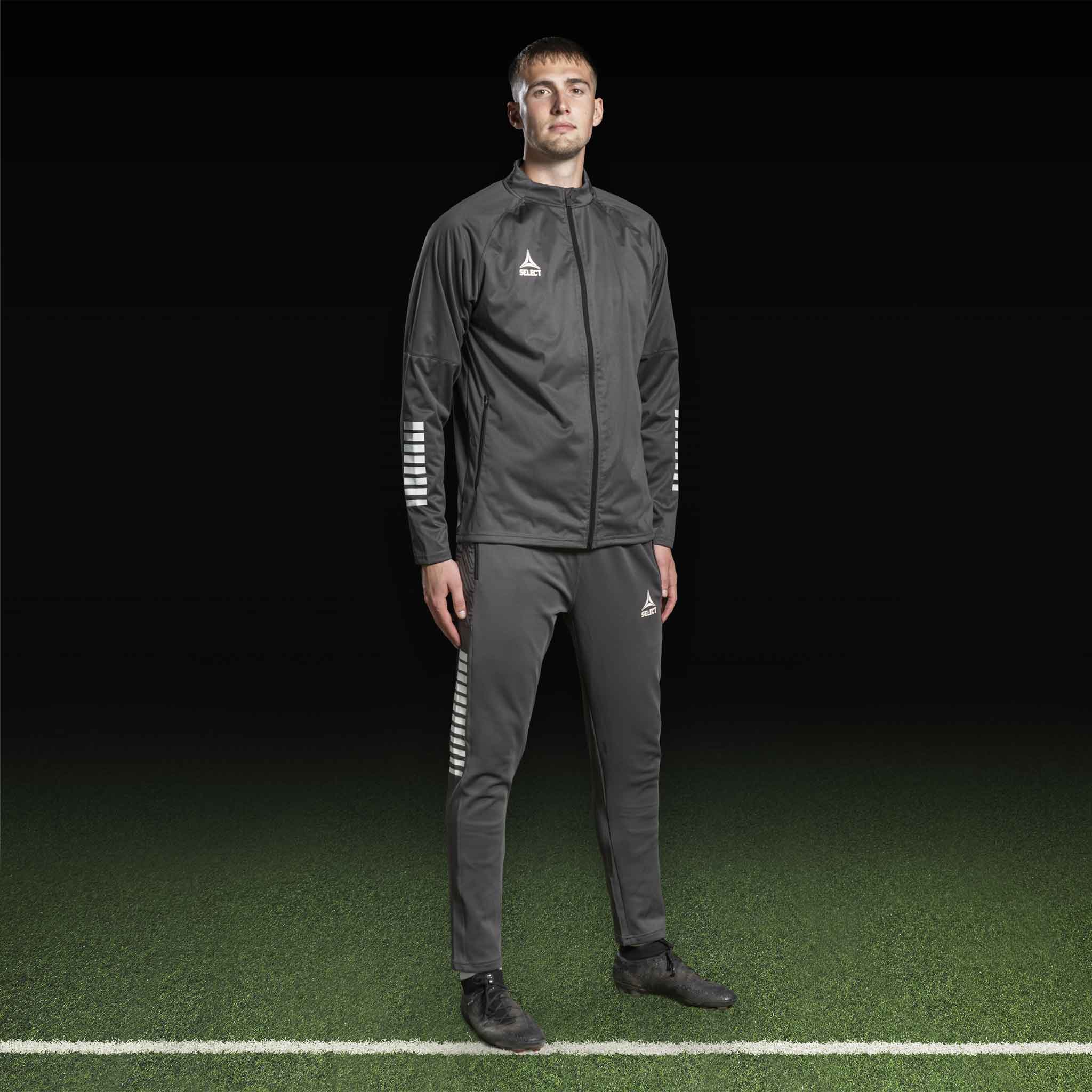 Manlig fotbollsspelare i grå och vit Training jacket Monaco v24, Match & Training wear, framifrån på planen.