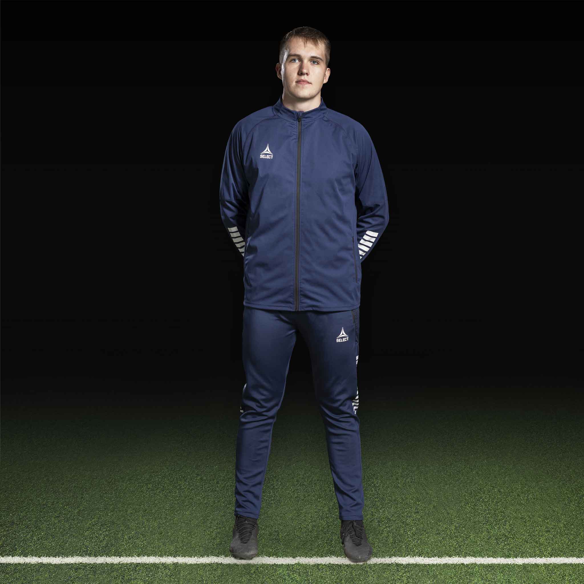 Manlig fotbollsspelare i marinblå Training jacket Monaco v24, Match & Training wear, med vit logga, framifrån på plan.
