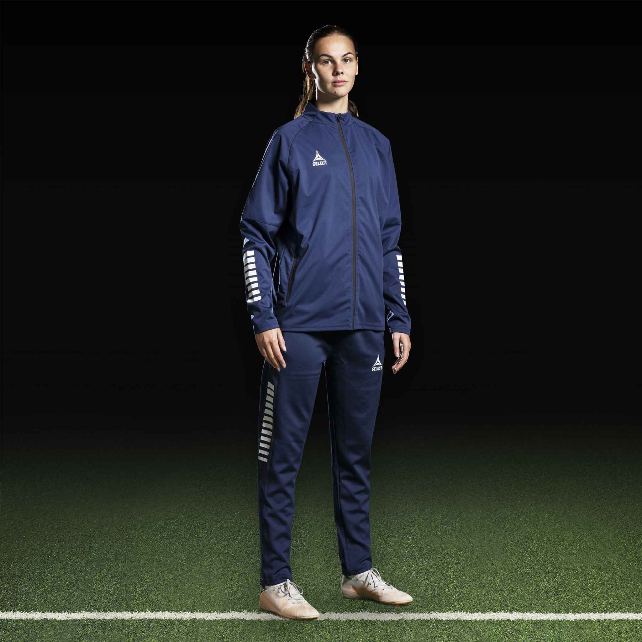 Kvinnlig fotbollsspelare i marinblå och vit Training jacket Monaco v24, Match & Training wear, framifrån.