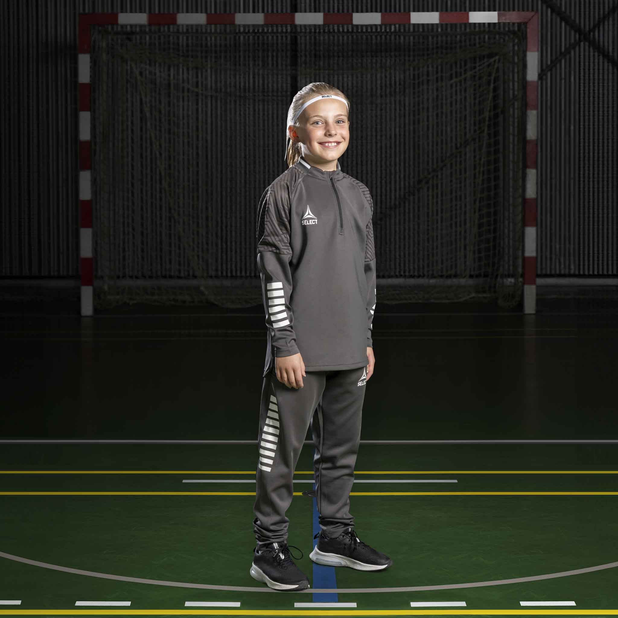 Flicka handbollsspelare i grå Training sweat 1/2 zip Monaco v24, Match & Training wear, med vita detaljer på plan.