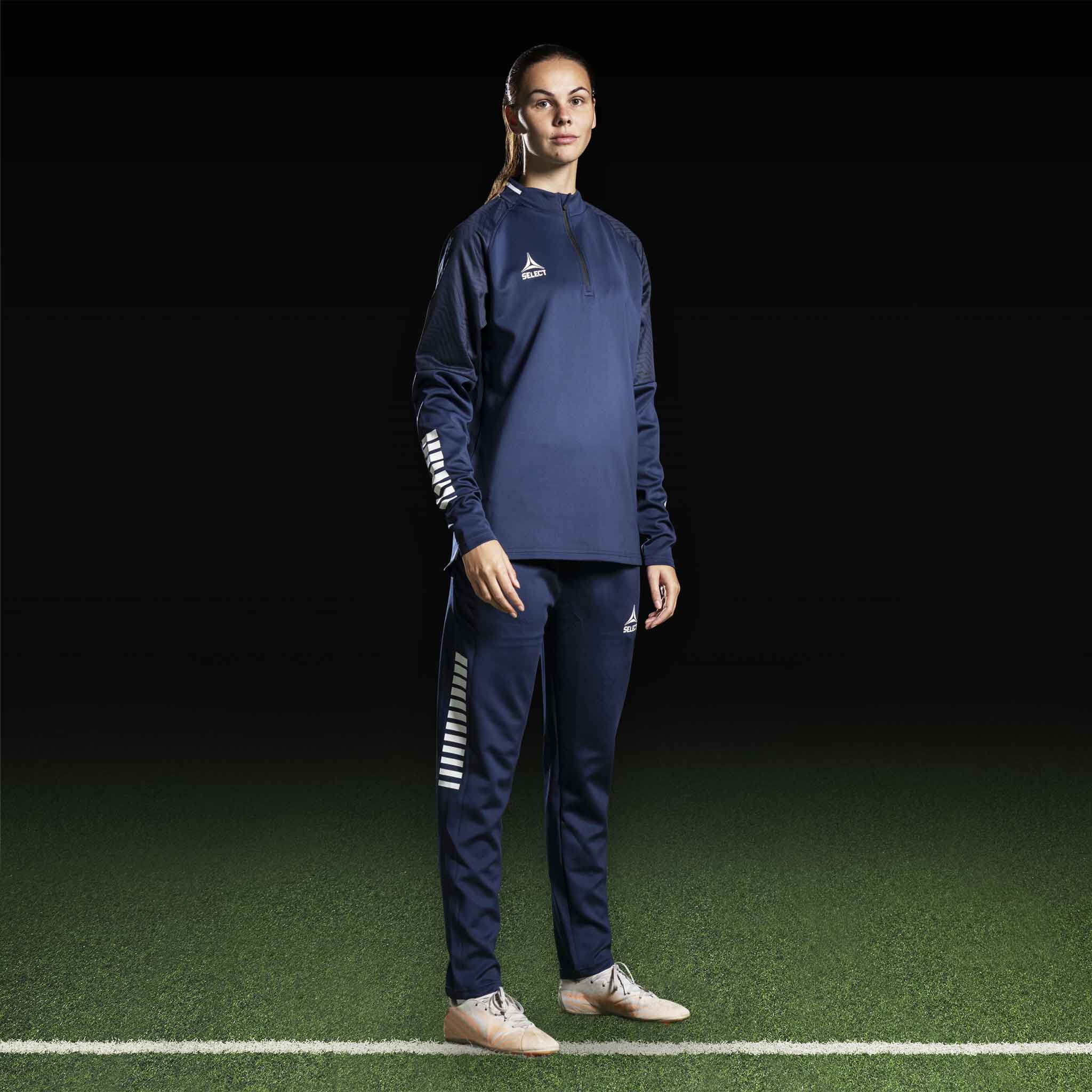 Kvinnlig fotbollsspelare i marinblå Training sweat 1/2 zip Monaco v24, Match & Training wear, med vita detaljer, framifrån.