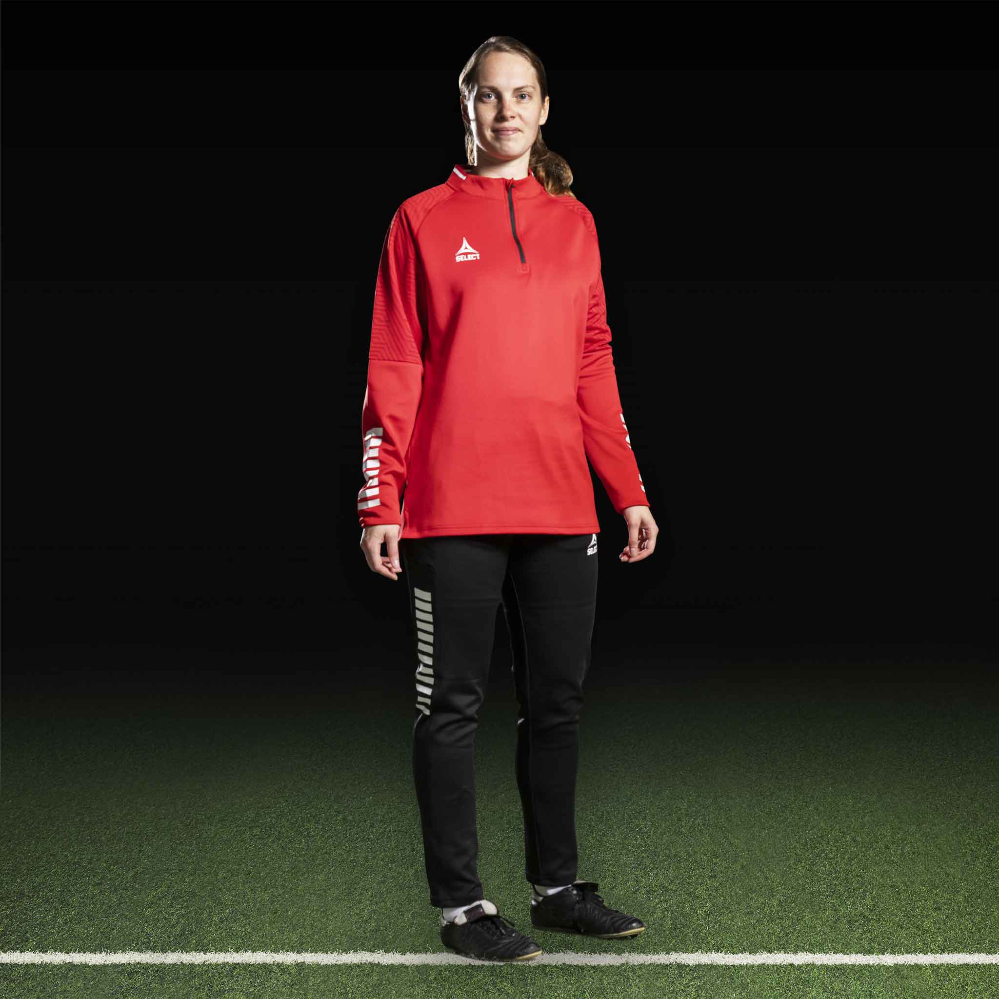 Kvinnlig fotbollsspelare i röd Training sweat 1/2 zip Monaco v24 och svarta byxor, Match & Training wear.