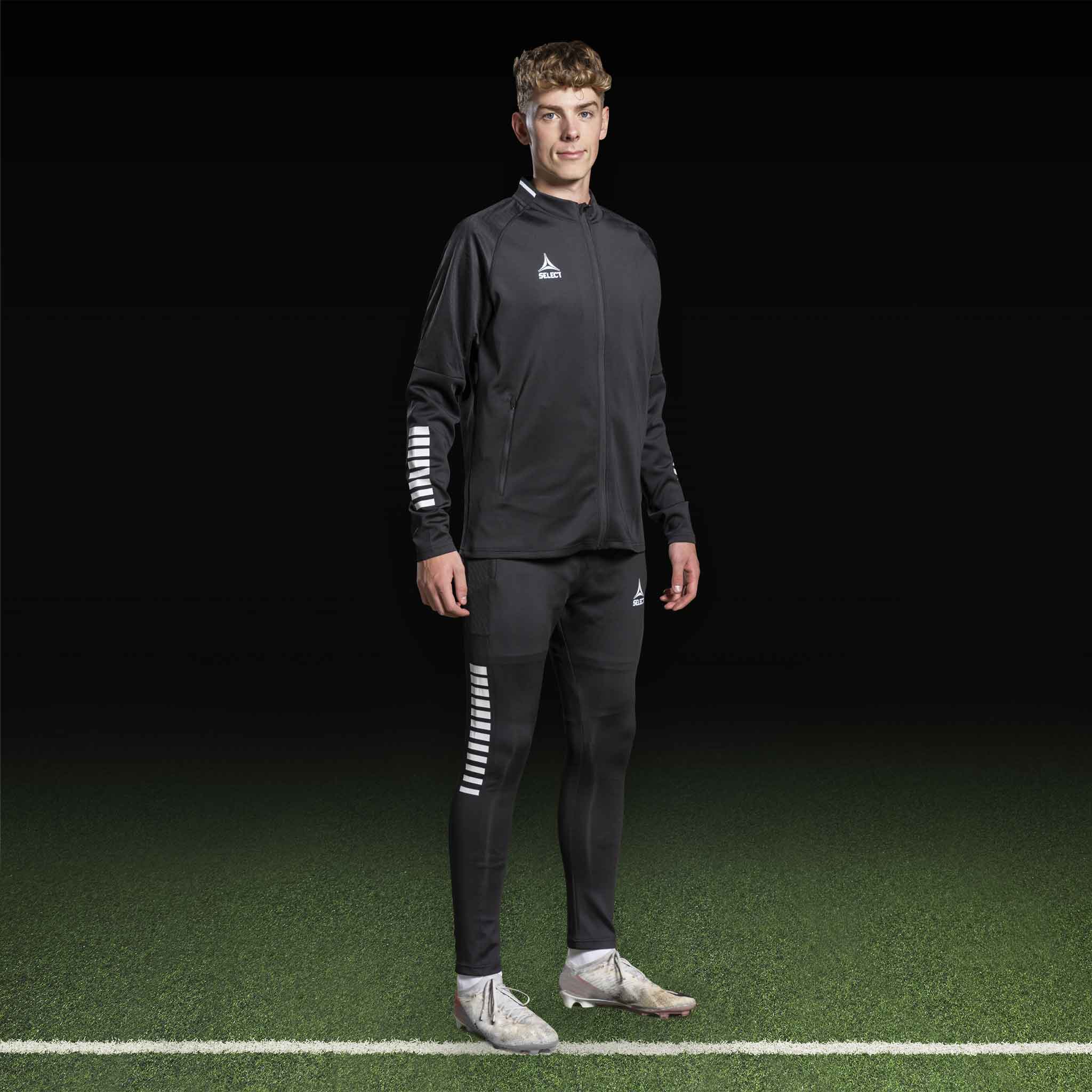 Manlig fotbollsspelare i svart-vit Zip jacket Monaco v24, Match & Training wear, framifrån på planen.
