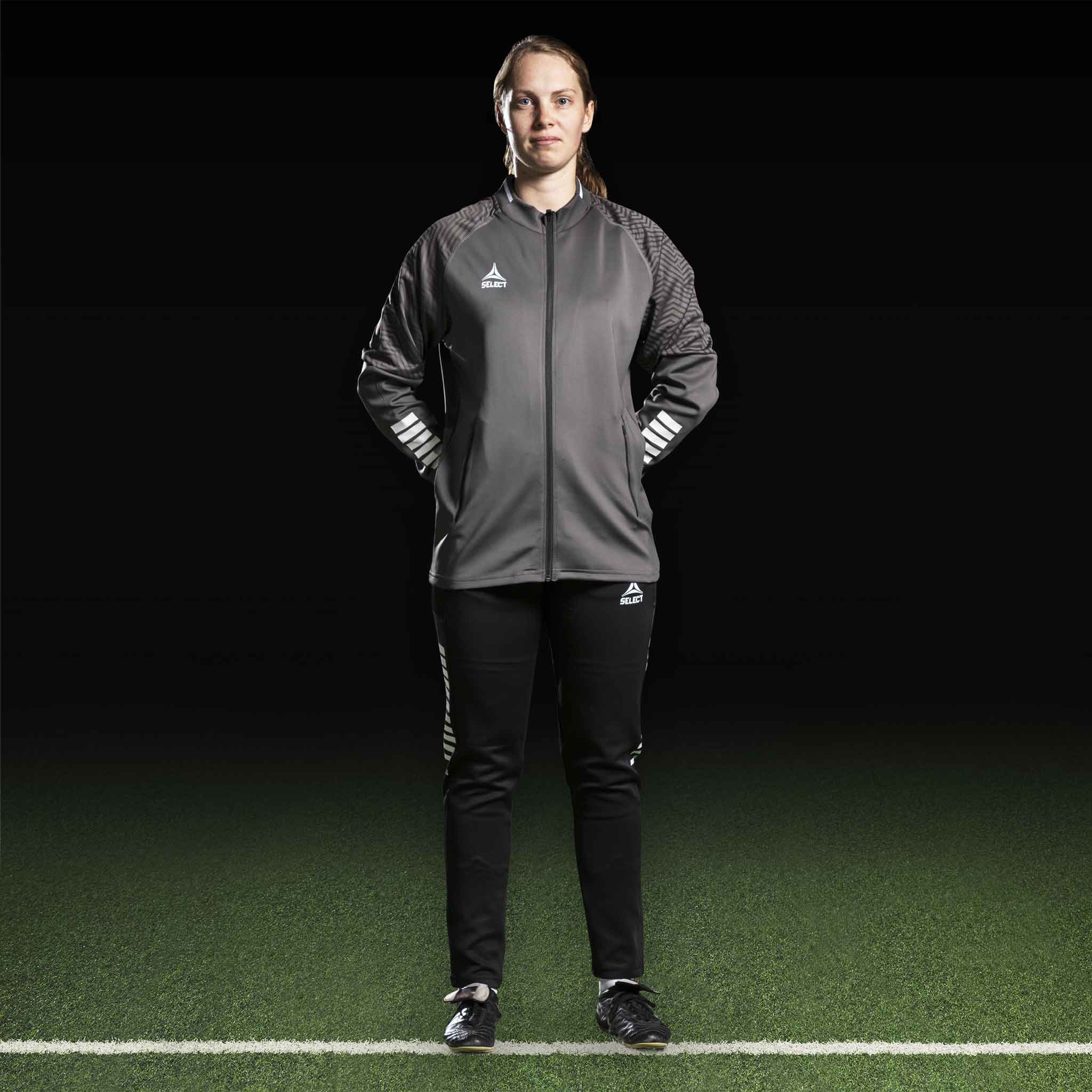 Kvinnlig fotbollsspelare i grå Zip jacket Monaco v24 och svarta byxor, Match & Training wear, framifrån.