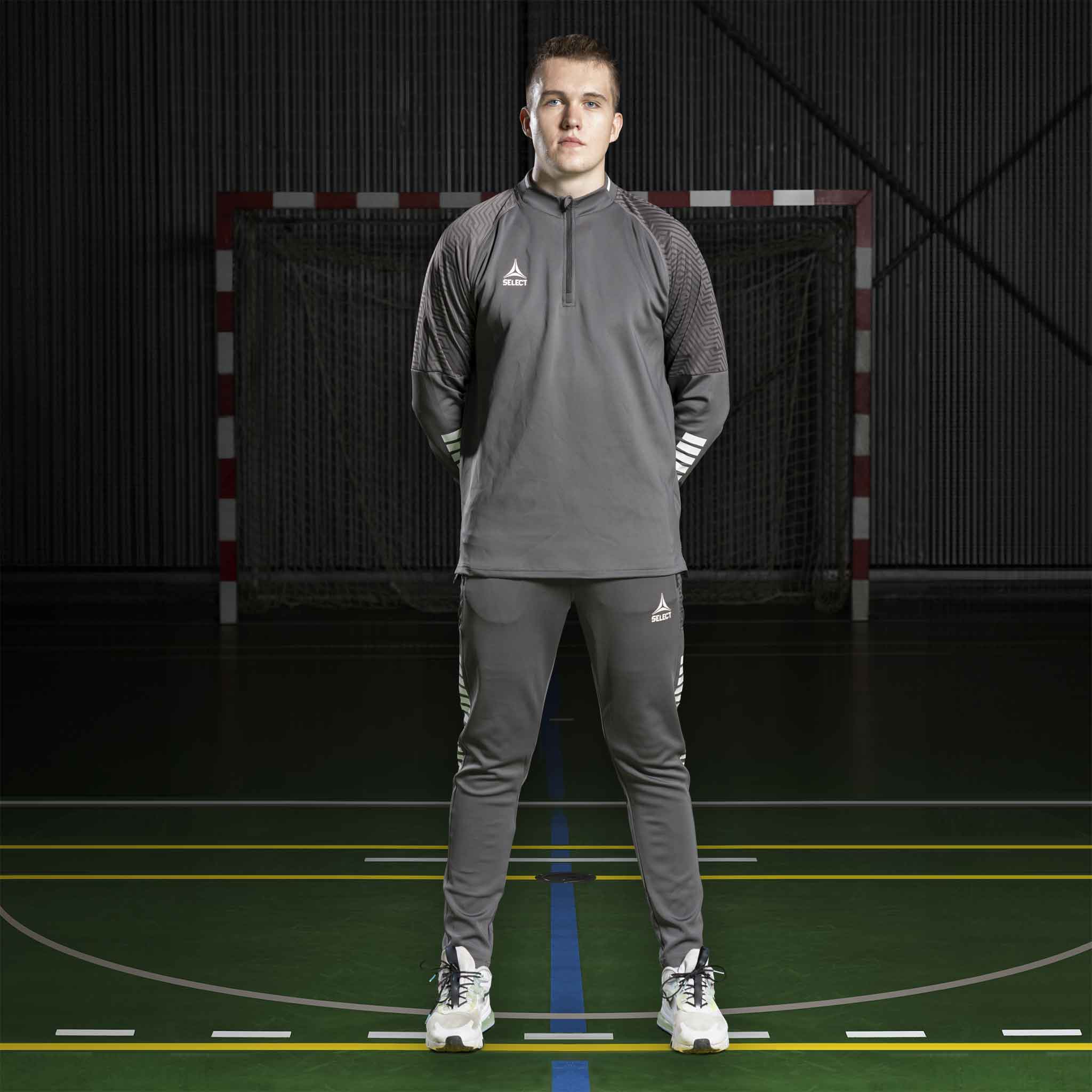 Manlig fotbollsspelare i grå Zip jacket Monaco v24 och matchande byxor, Match & Training-kläder, framifrån på inomhusplan.