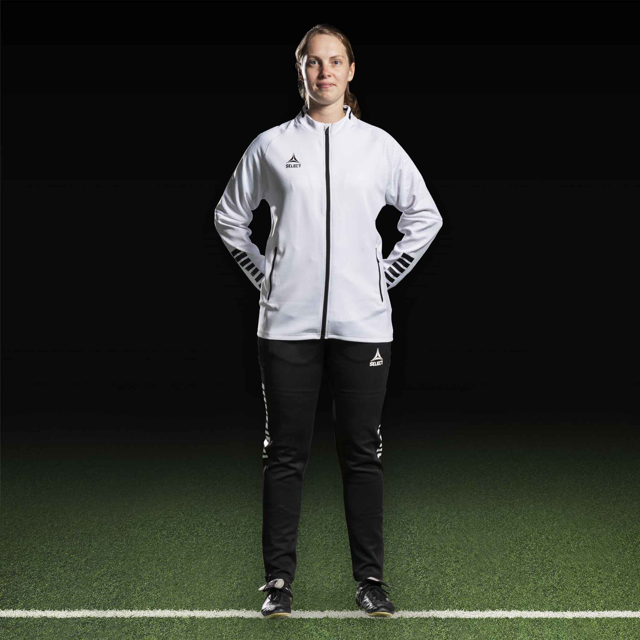Kvinnlig fotbollsspelare i vit Zip jacket Monaco v24 och svarta byxor, Match & Training wear, framifrån.