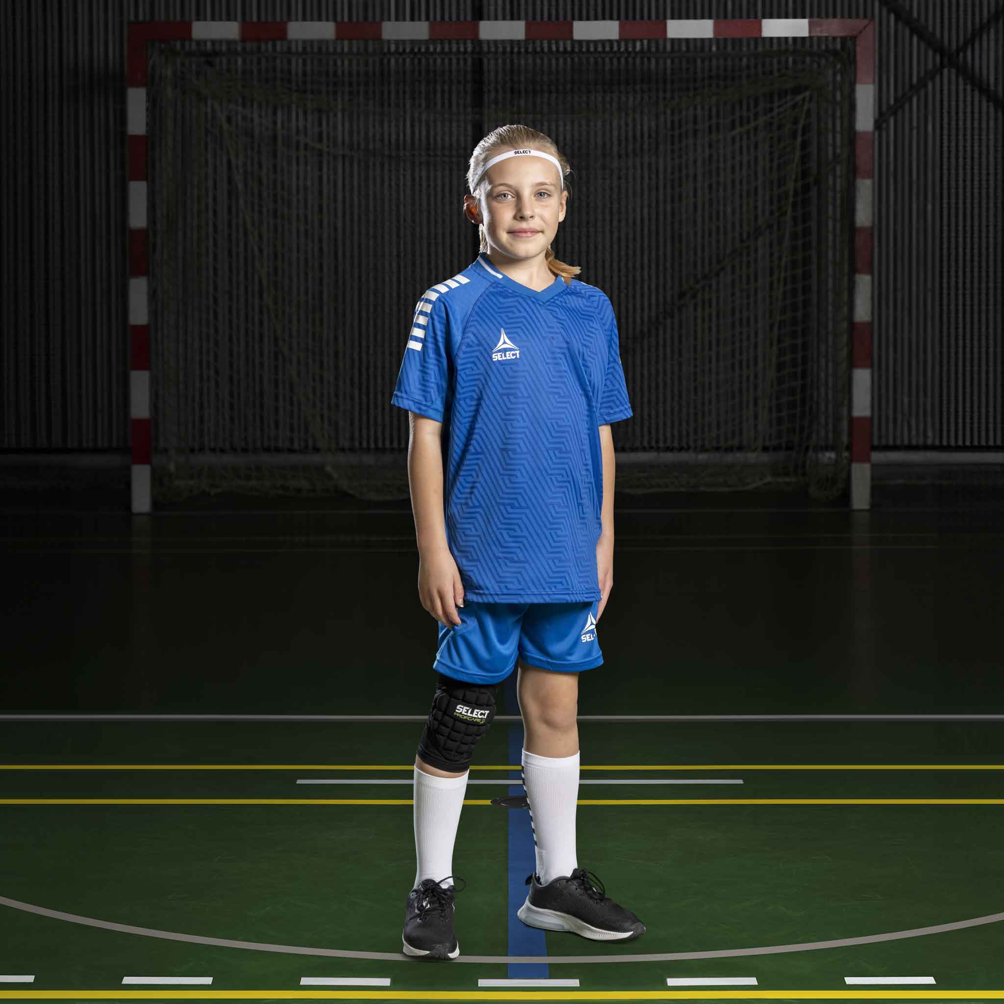 Flicka handbollsspelare i blå och vita Player shorts Monaco v24, Match & Training-kläder, framifrån på plan.