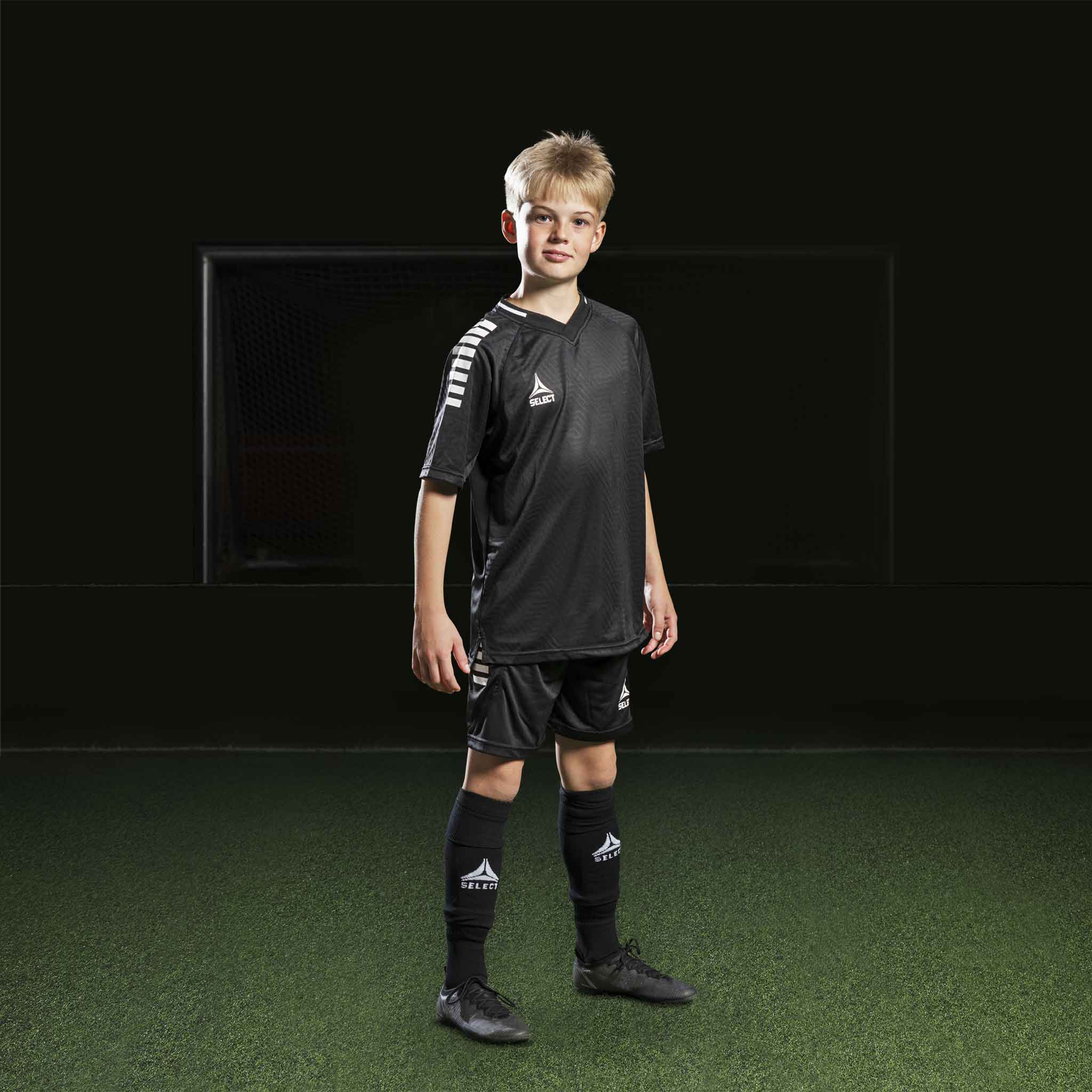 Pojke fotbollsspelare i svarta Player shorts Monaco v24, Match & Training wear, med matchande tröja och strumpor.