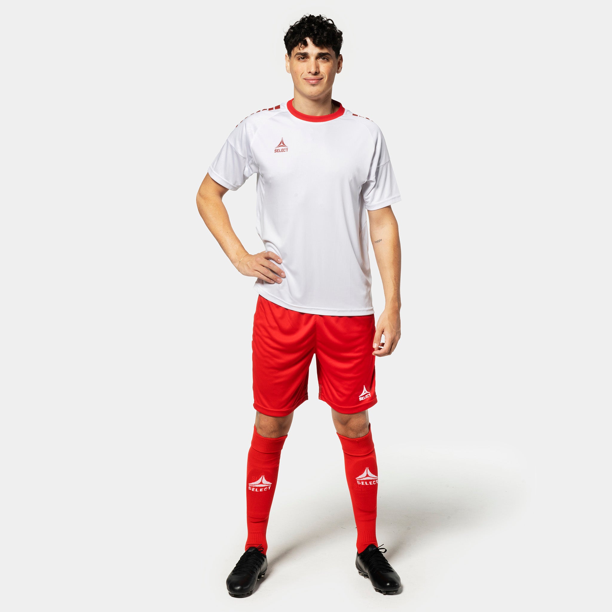 Manlig fotbollsspelare i vit tröja, röda Player shorts Spain v25 och röda strumpor. Match & Training wear.