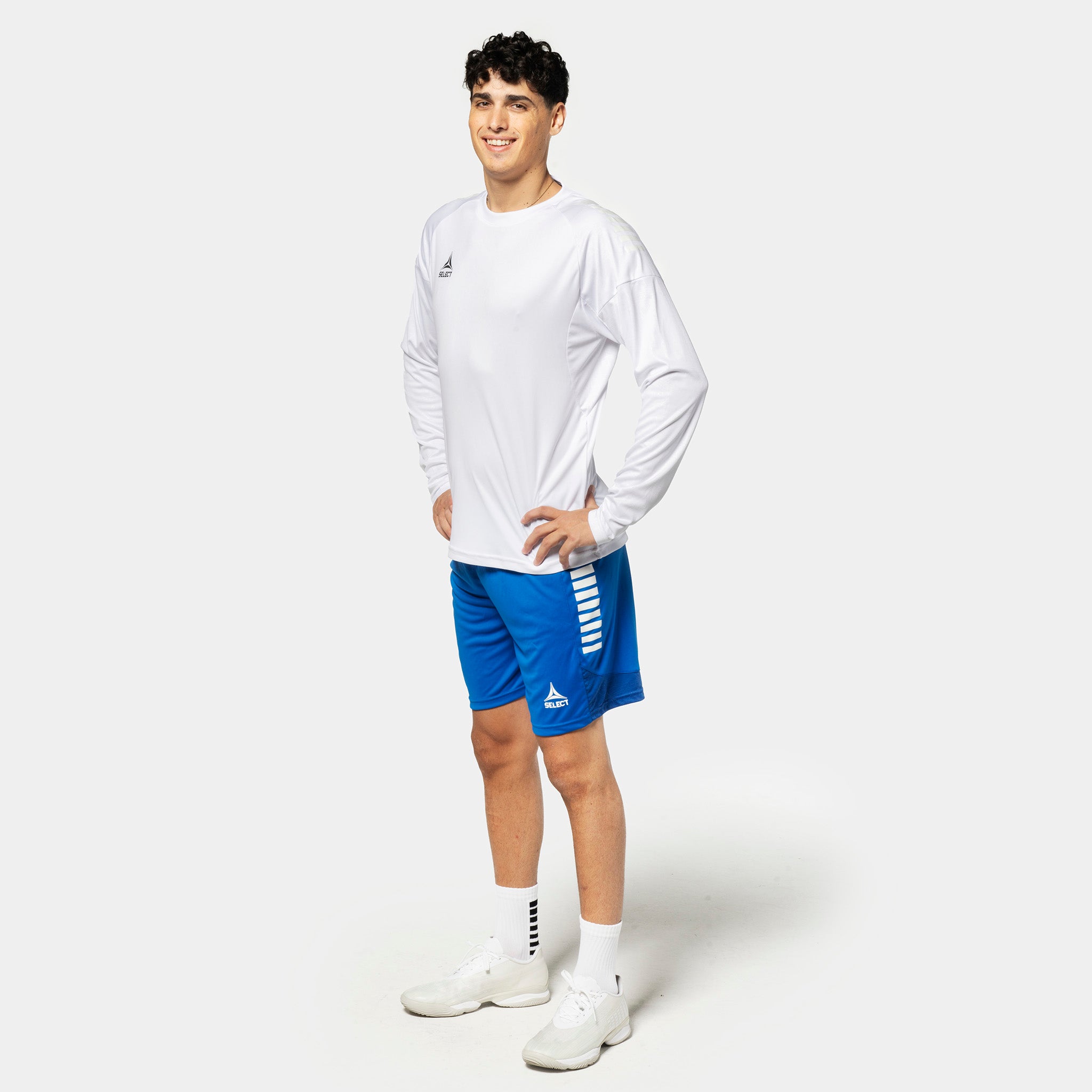 Manlig fotbollsspelare i vit Player shirt L/S Spain v25 och blå shorts, Match & Training wear.
