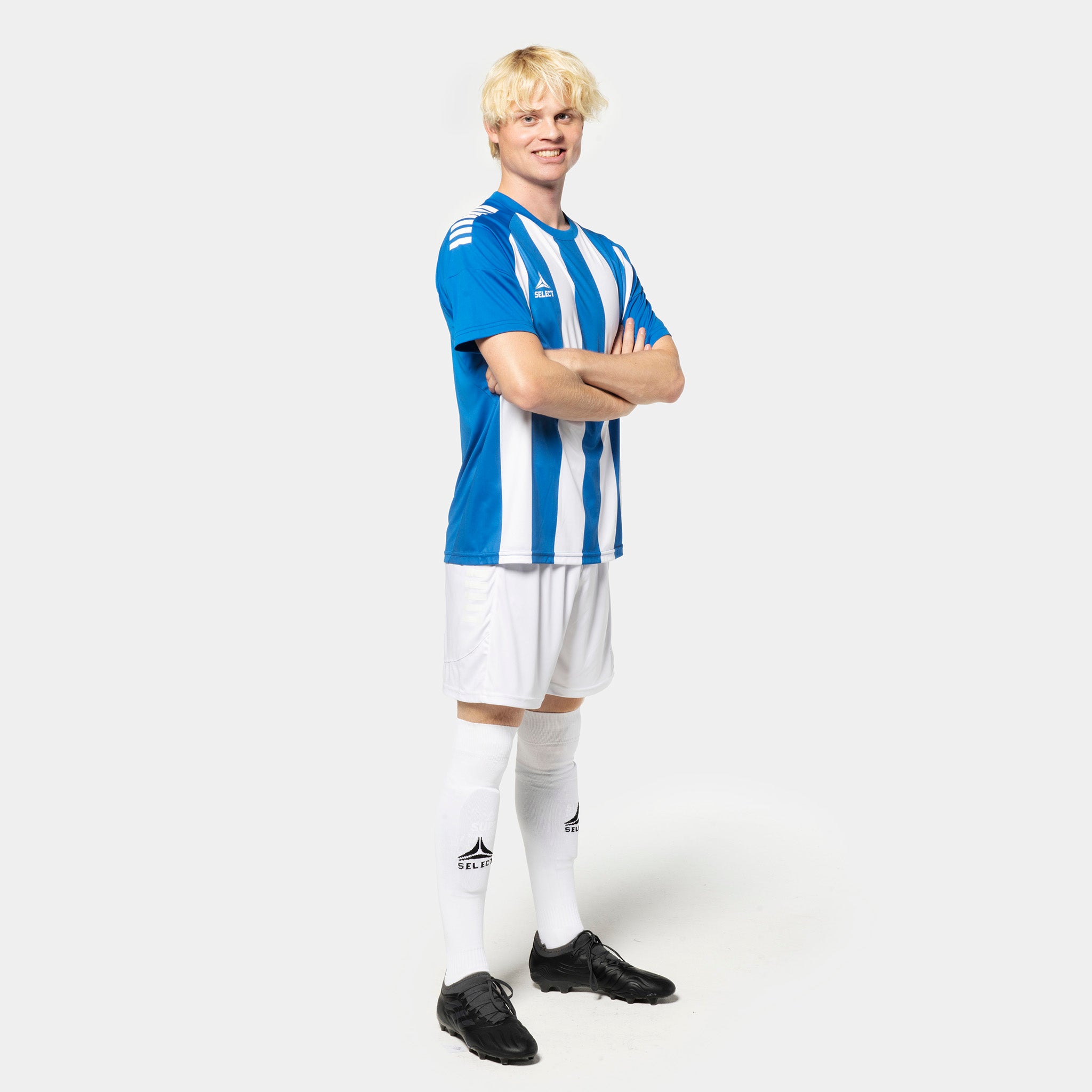 Manlig fotbollsspelare i blå- och vitrandig Player shirt S/S Spain striped v25, vita shorts och strumpor. Match & Training wear.