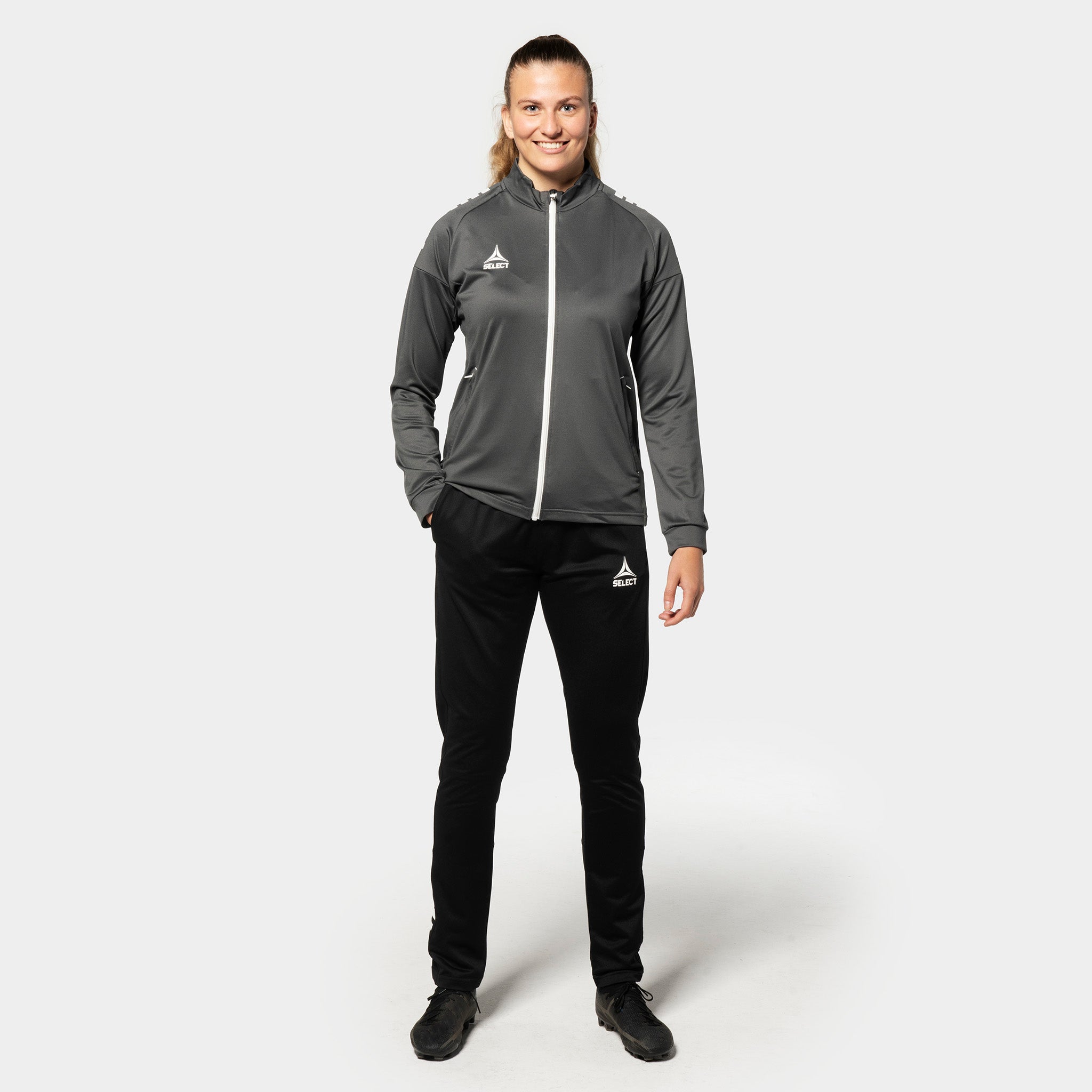 Kvinnlig fotbollsspelare i grå-vit Training zip jacket Spain woman v25, Match & Training wear, svarta byxor, framifrån