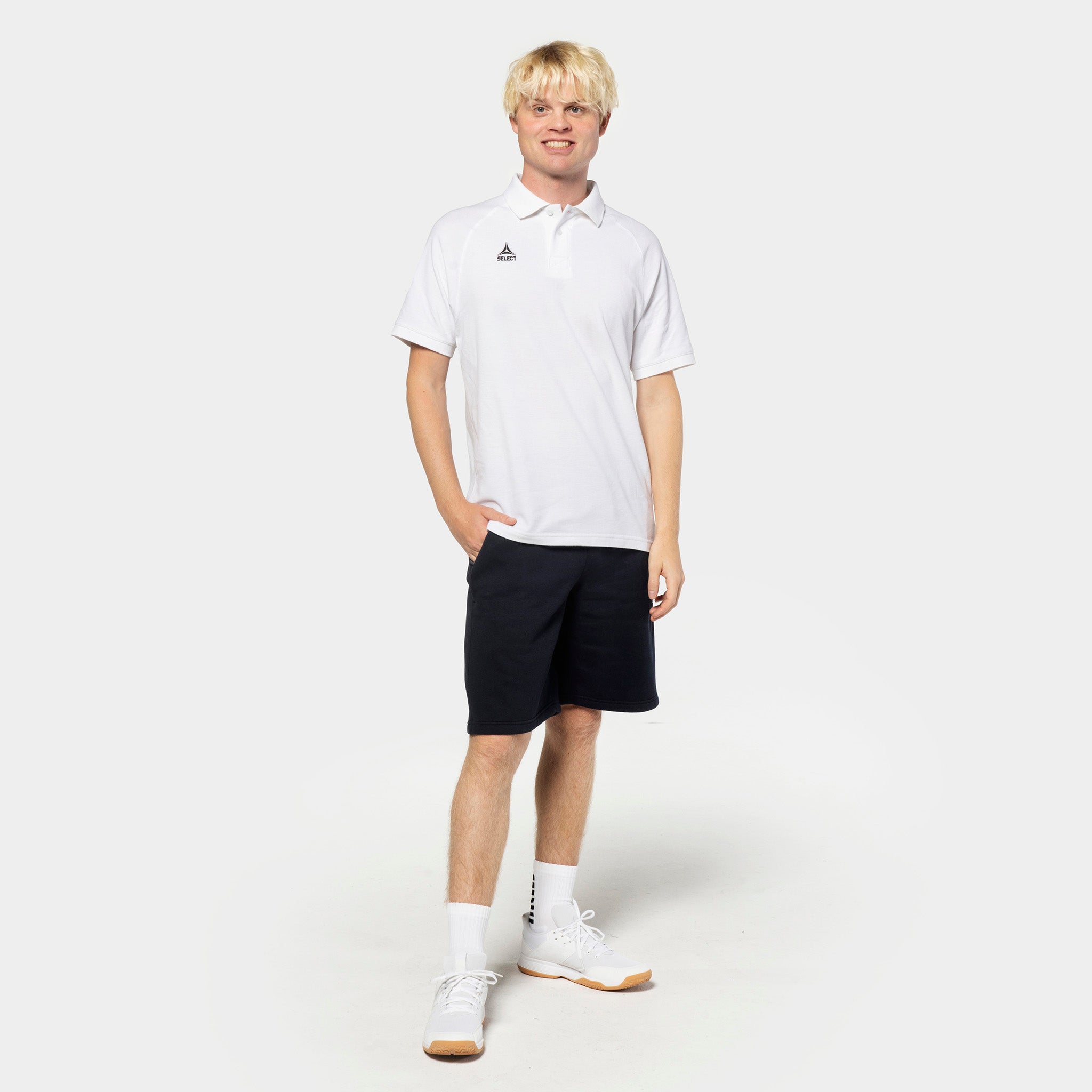 Manlig fotbollsspelare i vit piké och svarta Sweat shorts Oxford v25, fritidskläder, framifrån.