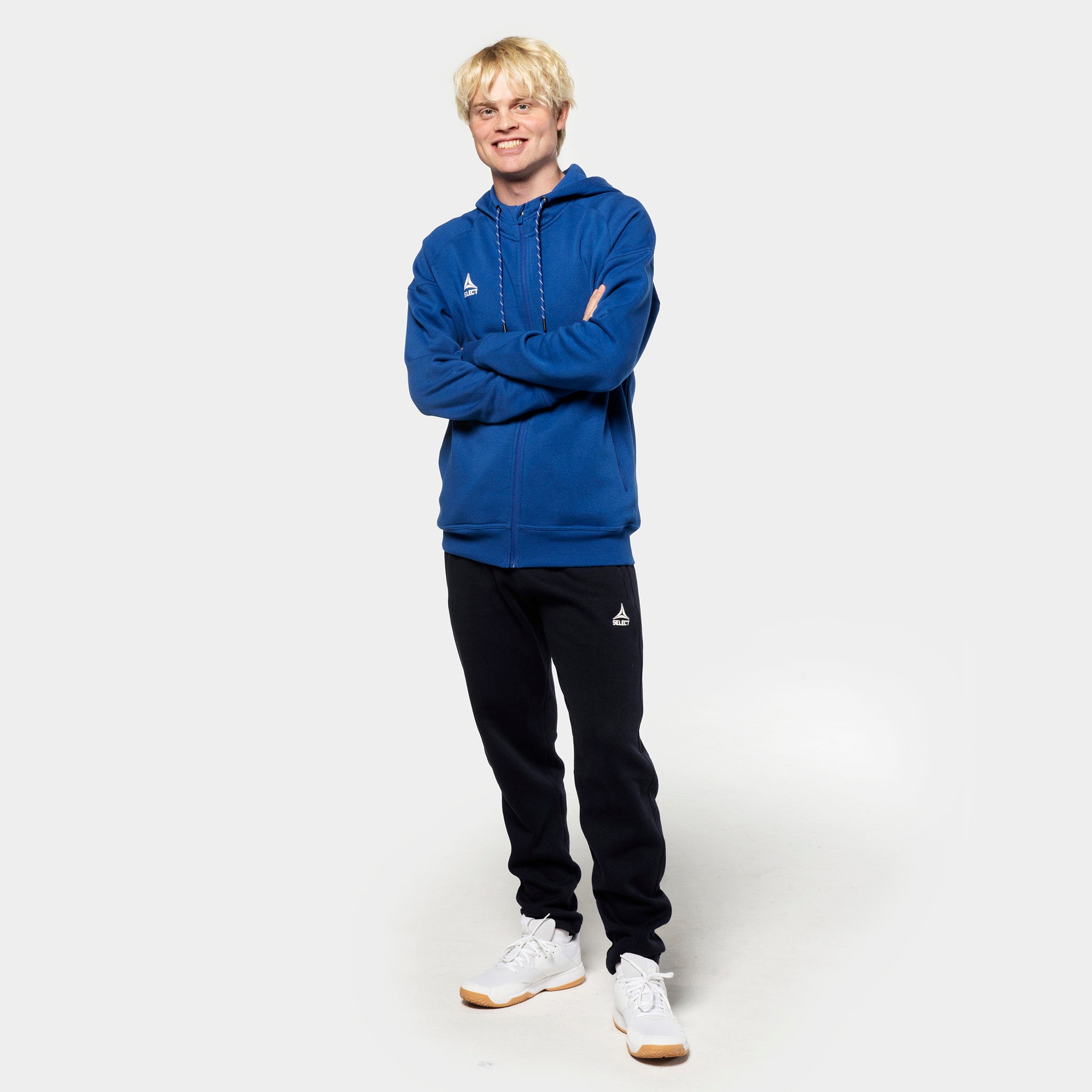 Manlig fotbollsspelare i blå zip hoodie och svarta Sweat pants Oxford v25, fritidskläder, framifrån.
