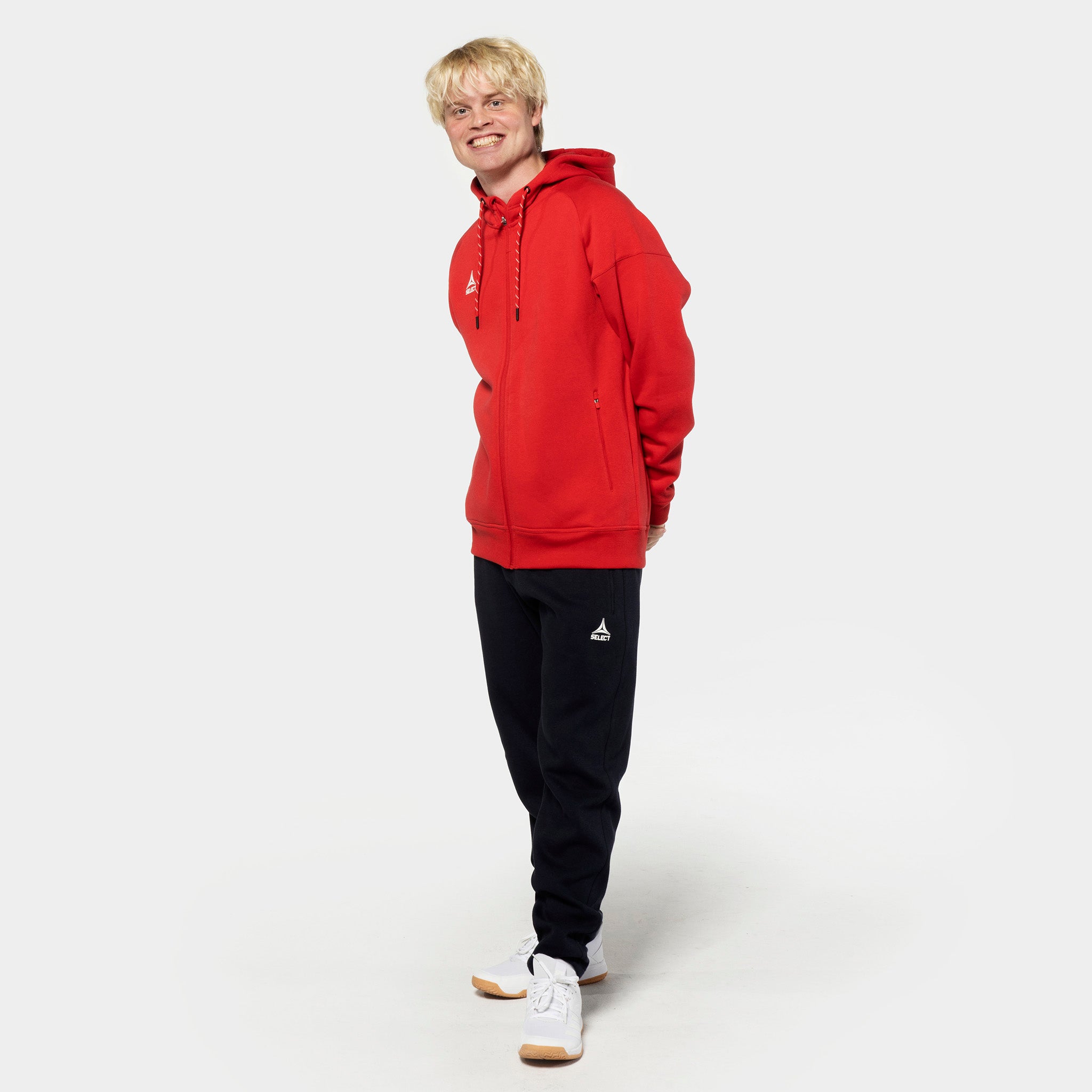 Manlig fotbollsspelare i röd zip hoodie och svarta Sweat pants Oxford v25 fritidskläder, framifrån.