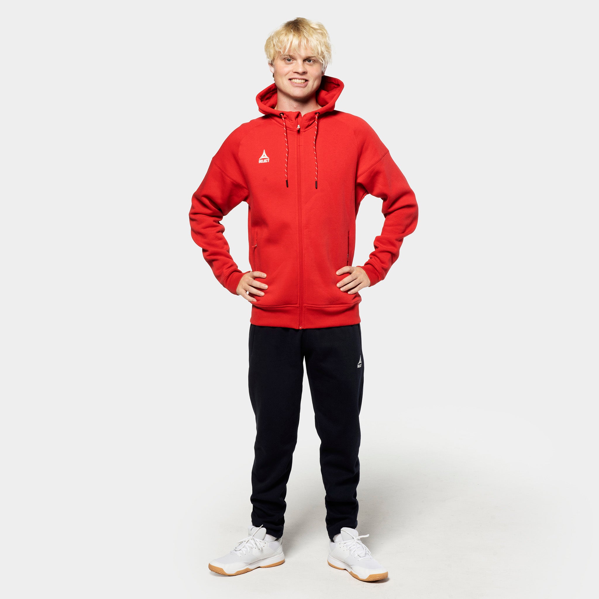 Manlig fotbollsspelare i röd zip-hoodie och svarta Sweat pants Oxford v25, fritidskläder, framifrån.