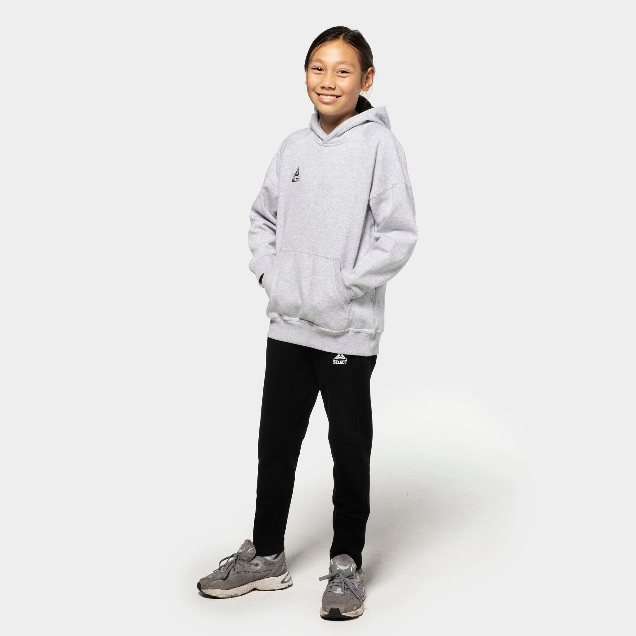Flicka fotbollsspelare i grå Oxford v25 hoodie och svarta Sweat pants Oxford v25 fritidskläder, framifrån.