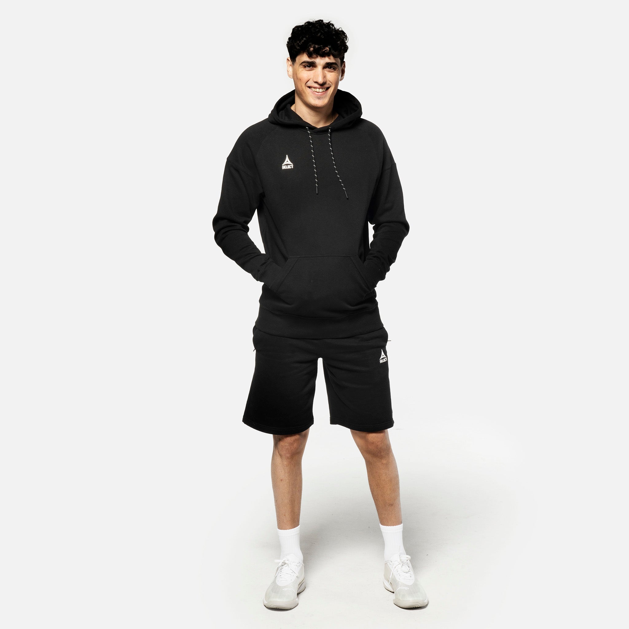 Manlig fotbollsspelare i svarta Sweat shorts Oxford v25 och svart hoodie, fritidskläder, framifrån.
