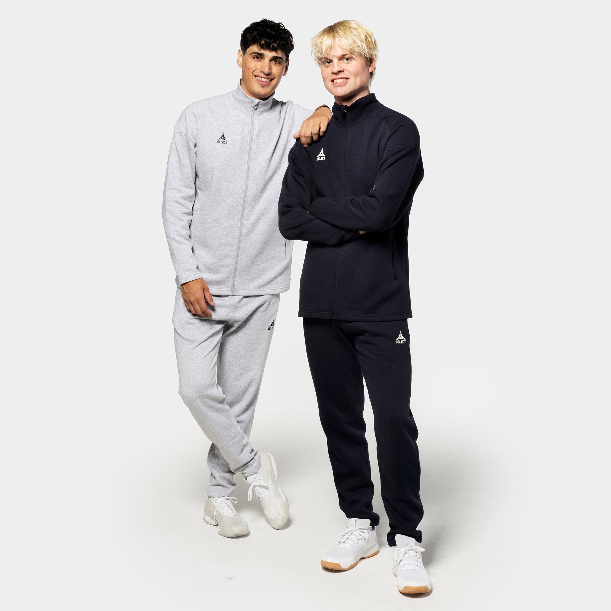 Två manliga fotbollsspelare i fritidskläder visar Sweat pants Oxford v25 i grått och svart med matchande zipjackor.