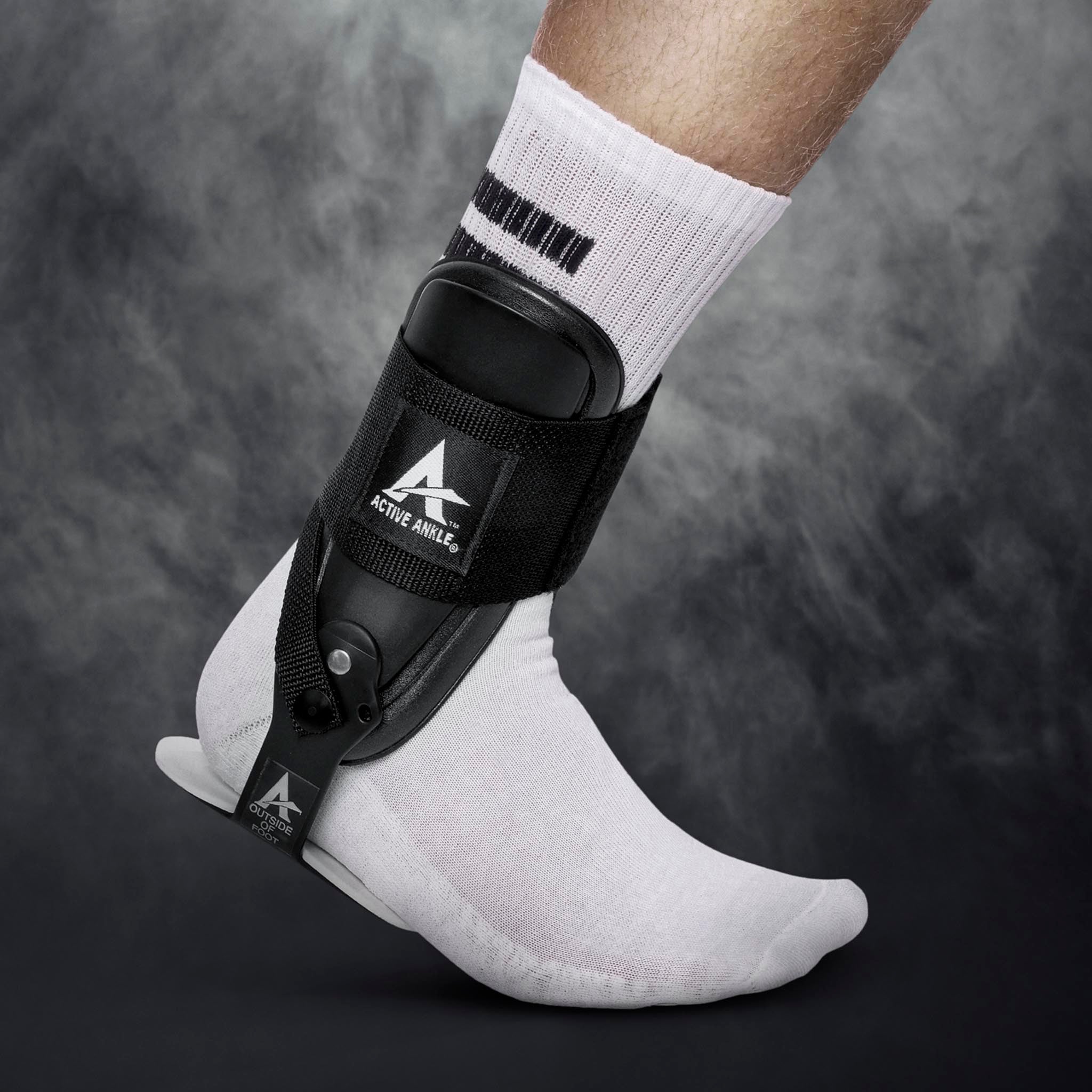Sort Active Ankle T-2 sportsstøtte båret på en fodboldspillers fod med hvid sok, set forfra
