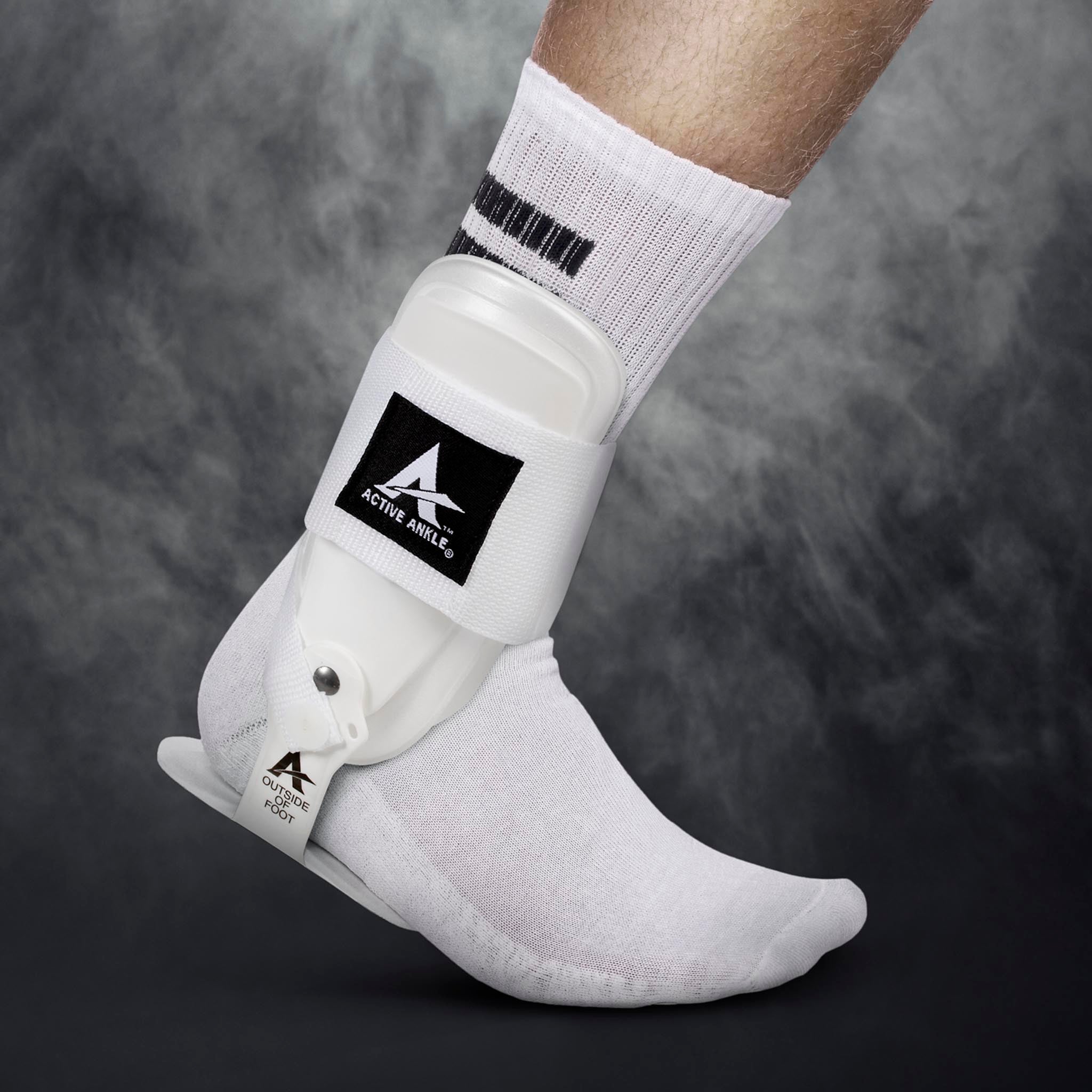 Hvid Active Ankle T-2 sportsstøtte båret på en fodboldspillers fod, modelbillede.